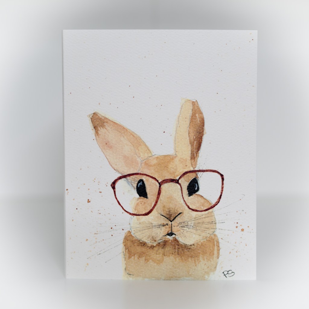 A greeting card featuring a painting of a brown bunny wearing red glasses.