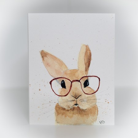 A greeting card featuring a painting of a brown bunny wearing red glasses.