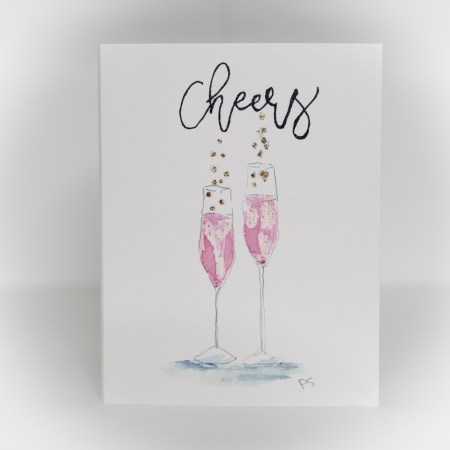 A greeting card featuring a painting of two glasses of pink bubbly liquid and says cheers above.