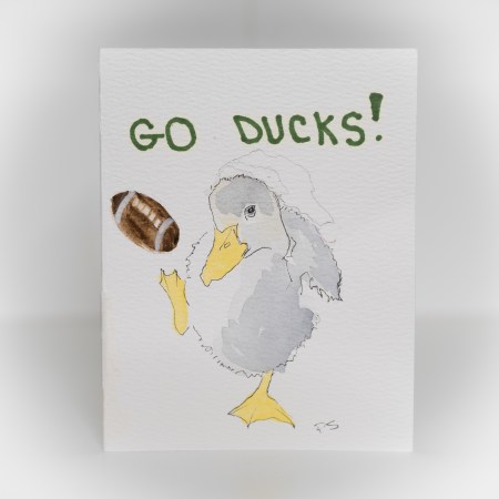 A greeting card featuring a painting of a duck kicking a football that says "Go Ducks!"